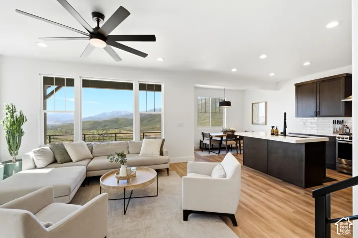 Spacious living area featuring large windows, wood-finish flooring, recessed lighting, and a modern ceiling fan