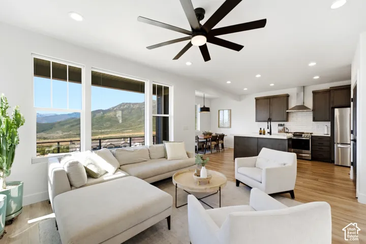Open-concept living area with wood-finish flooring, recessed lighting, and a contemporary ceiling fan