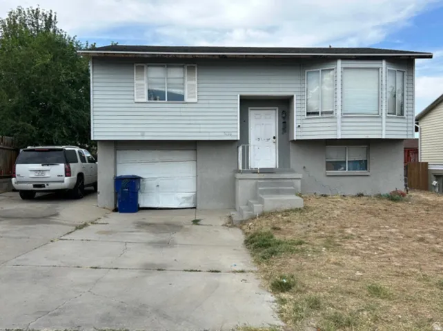 Split-level residence featuring light-colored siding and a concrete foundation