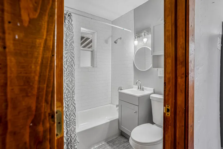 Contemporary bathroom featuring a subway-tiled shower, white bathtub, modern vanity with integrated sink, and wall-mounted storage cabinet