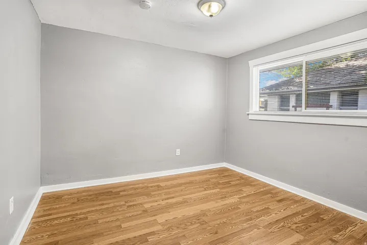 Light gray walls, wood-finish flooring, white trim, and a semi-flush mount ceiling light