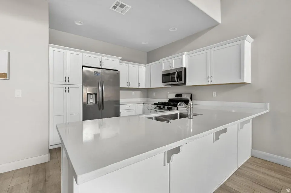 Kitchen featuring white shaker-style cabinetry, a stainless steel French door refrigerator, a gas range, and a microwave