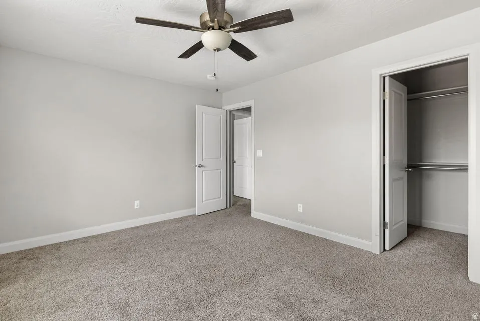 Plush carpet flooring complemented by a ceiling fan with integrated lighting