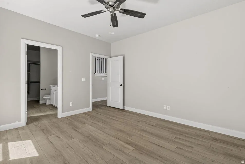 Wood-finish flooring throughout, ceiling fan with integrated lighting, recessed lighting, and a white vanity with a rectangular basin