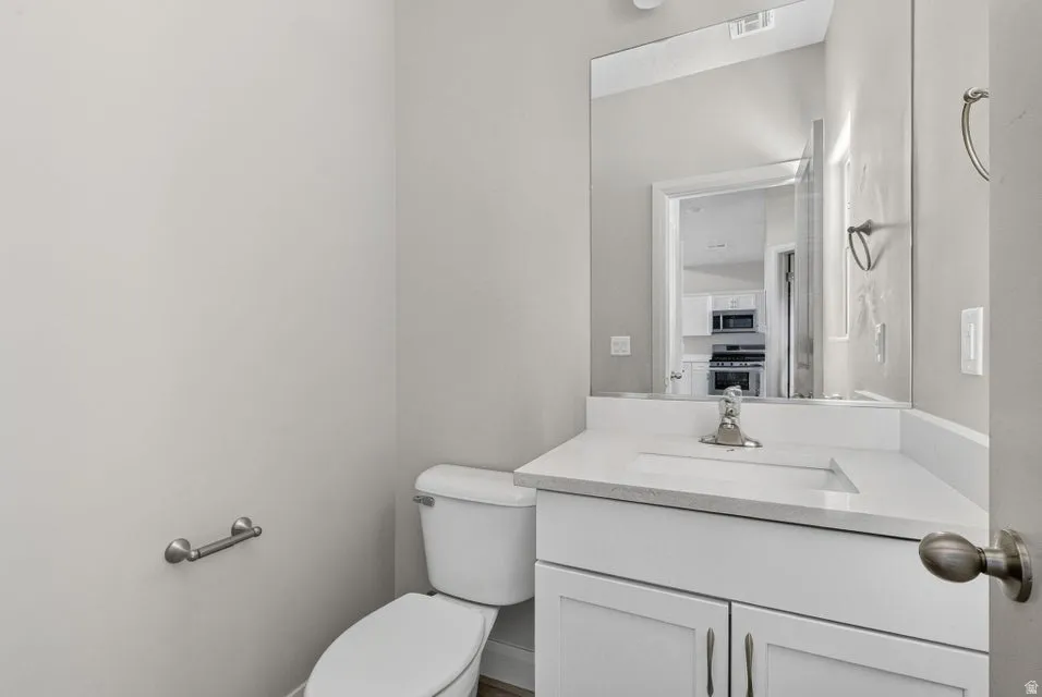 White vanity with under-mount sink, chrome faucet, and mirrored wall