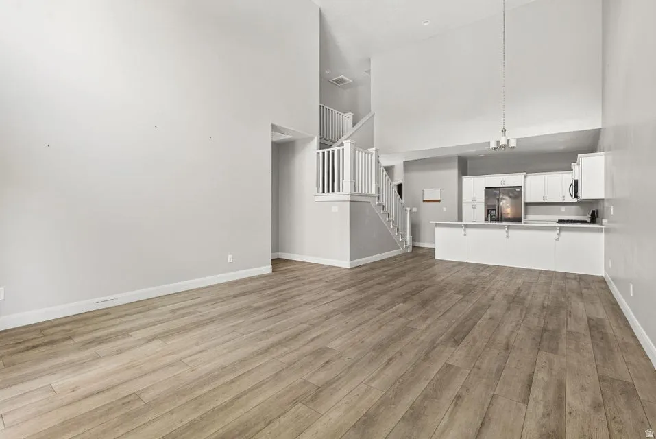Vaulted ceilings, wood-finish flooring, white cabinetry, white countertops, and a white staircase with balusters