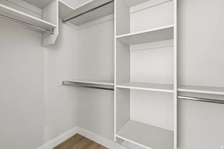 Built-in closet system with multiple shelving units, hanging rods, and wood-finish flooring