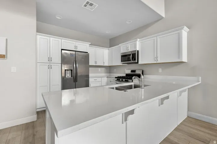 Kitchen featuring white shaker-style cabinetry, a stainless steel French door refrigerator, a gas range, and a microwave