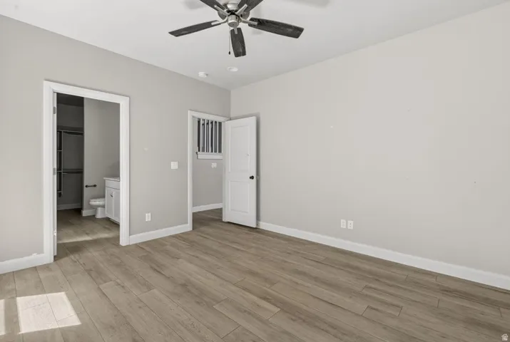 Wood-finish flooring throughout, ceiling fan with integrated lighting, recessed lighting, and a white vanity with a rectangular basin
