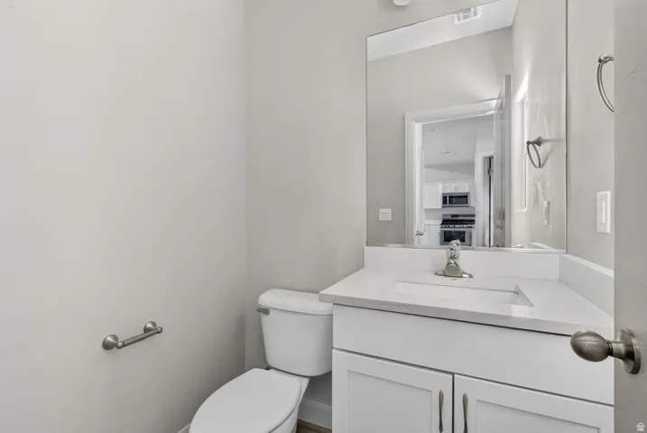 White vanity with under-mount sink, chrome faucet, and mirrored wall