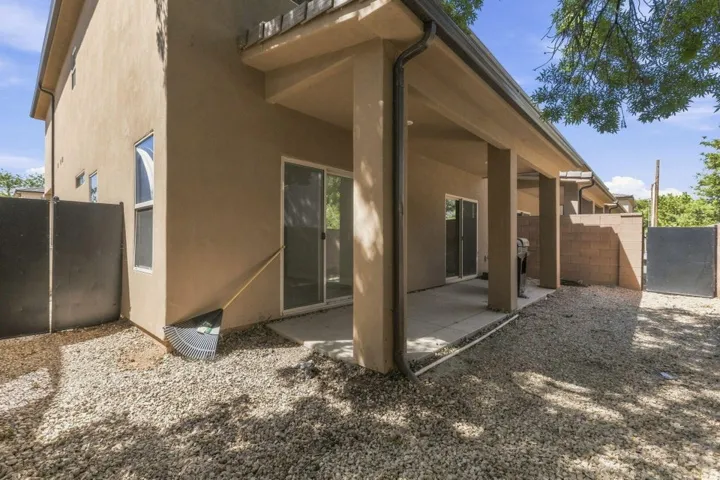 Covered patio with a concrete slab, multiple sliding glass doors, stucco exterior, and a gravel yard