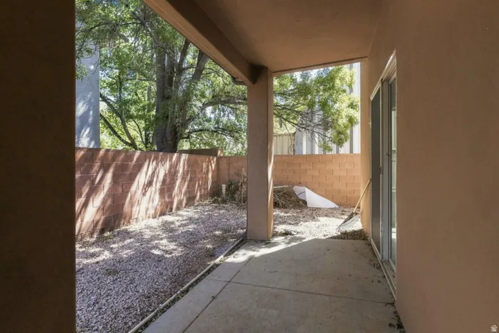 Covered concrete patio with stucco exterior, sliding glass door, and gravel ground cover