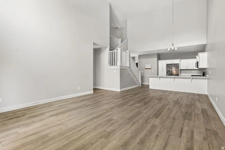 Vaulted ceilings, wood-finish flooring, white cabinetry, white countertops, and a white staircase with balusters
