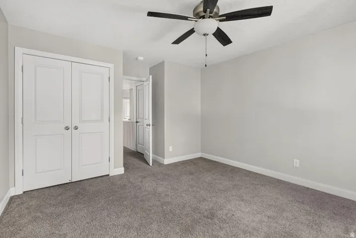 Neutral-toned walls, plush carpeting, and a ceiling fan with integrated lighting
