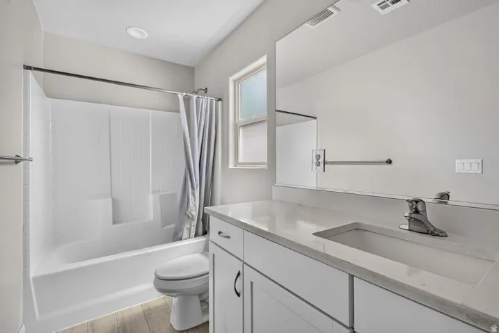 White vanity with a light-colored countertop, integrated sink, and chrome faucet