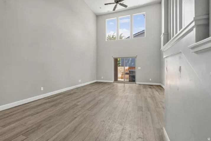 High ceilings with a ceiling fan, wood-finish flooring, and multiple transom windows