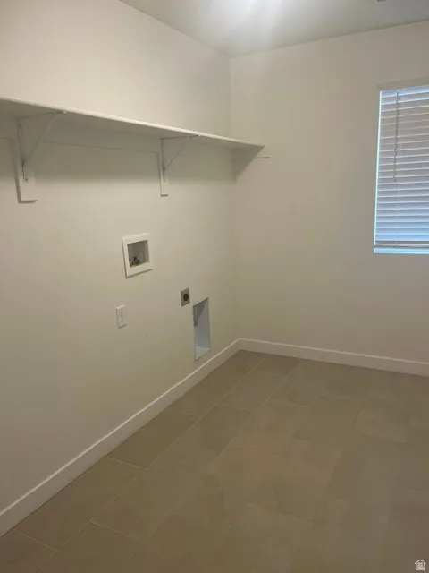 Utility area featuring a wide shelving unit, tiled flooring, and a window with blinds