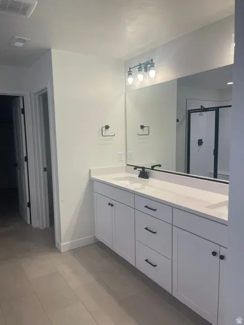 Dual-sink vanity with white cabinetry, matte black hardware, and an expansive mirror