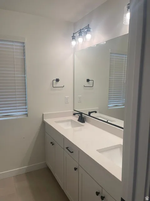 Double vanity with undermount sinks and light-toned countertops, matte black plumbing fixtures, and white cabinetry