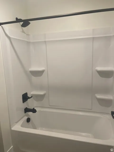 White tub and shower combination with a matte black shower head, faucet, and tub spout