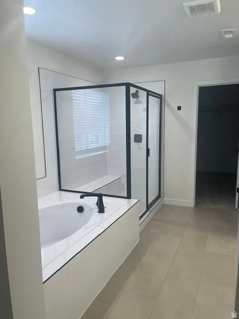 Built-in soaking tub with a matte black faucet, glass-enclosed shower with a bench, and a tile shower surround