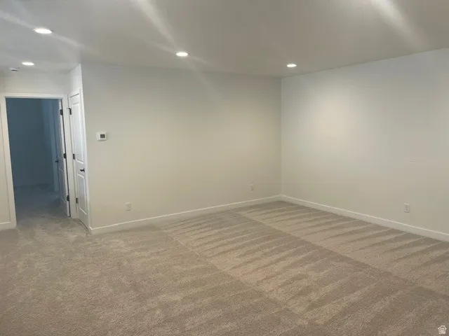 Recessed ceiling lighting, light neutral wall paint, white trim, and light-colored carpet