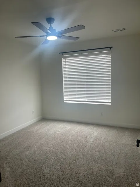 Neutral toned walls, light-colored carpeting, window with horizontal blinds, and a ceiling fan with integrated lighting