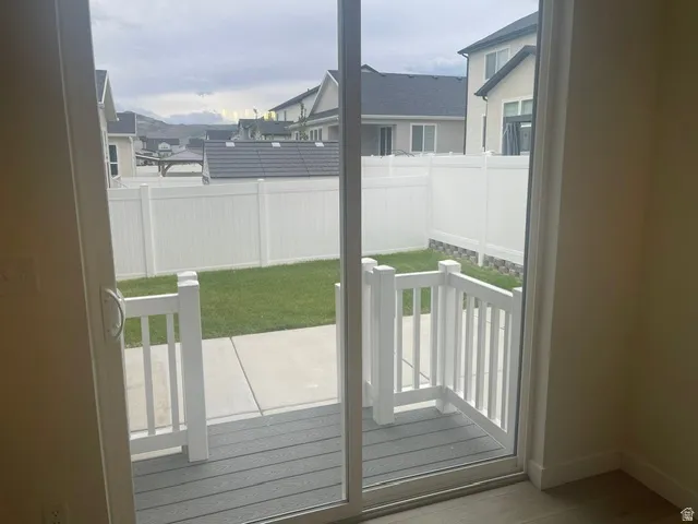 Sliding glass door opening to a private deck with railing, concrete patio, and fenced yard