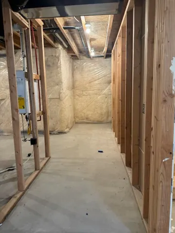 Unfinished space featuring wood framing, concrete flooring, and exposed ceiling joists