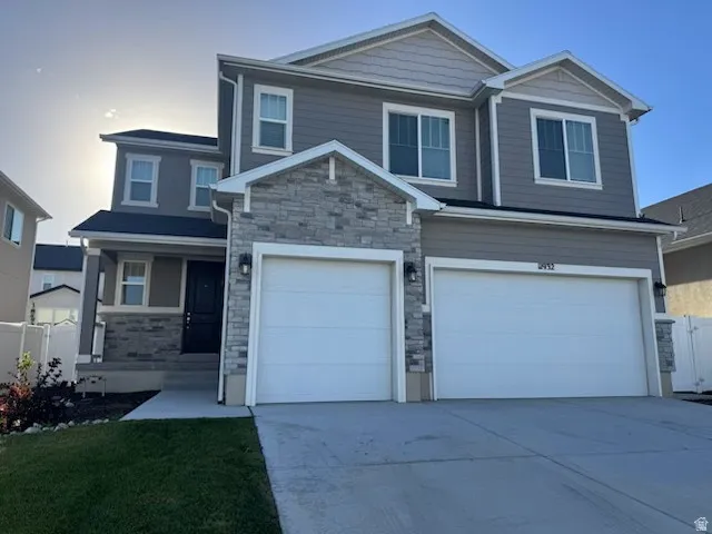 Two-story exterior featuring a stone and siding facade, a two-car garage, and a covered entry