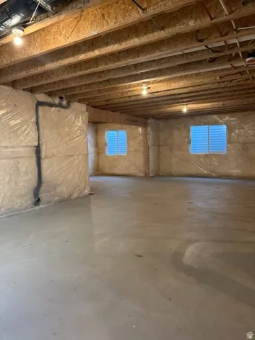 Exposed wood beam ceiling with recessed lighting, insulated perimeter walls, and a concrete floor