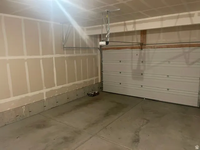 Attached garage with a concrete floor, automatic garage door opener, and unfinished walls