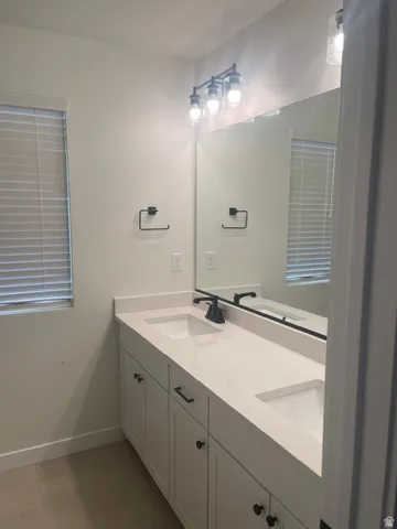 Double vanity with undermount sinks and light-toned countertops, matte black plumbing fixtures, and white cabinetry