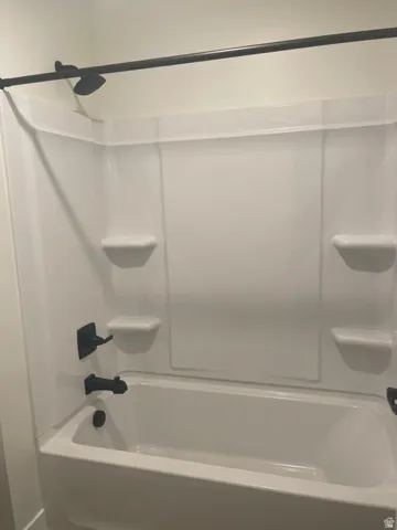 White tub and shower combination with a matte black shower head, faucet, and tub spout