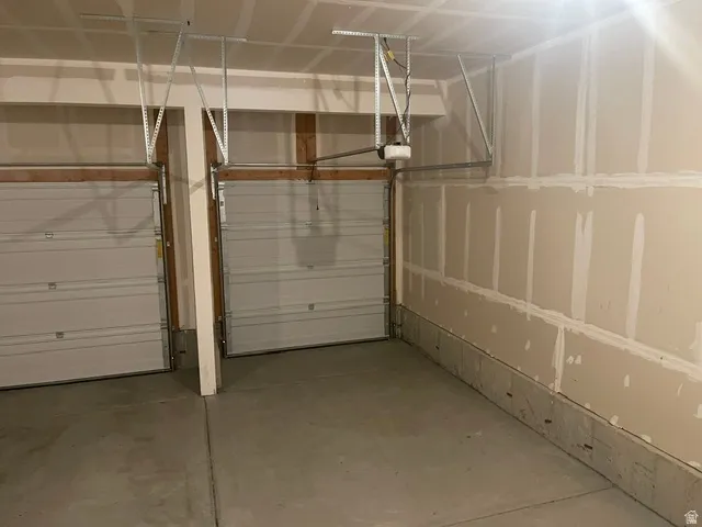 Two overhead garage doors, concrete flooring, and unfinished drywall