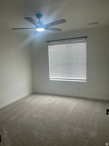 Neutral toned walls, light-colored carpeting, window with horizontal blinds, and a ceiling fan with integrated lighting