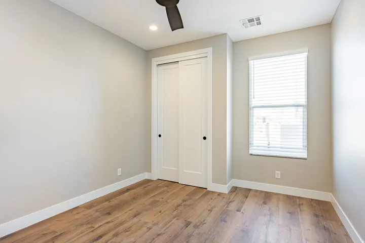 Wood-finish flooring, white baseboards, and a window with blinds