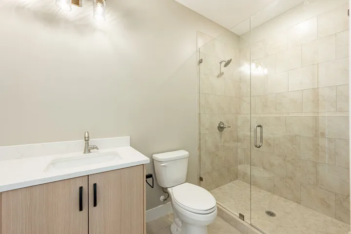Walk-in shower with clear glass enclosure and tiled surround