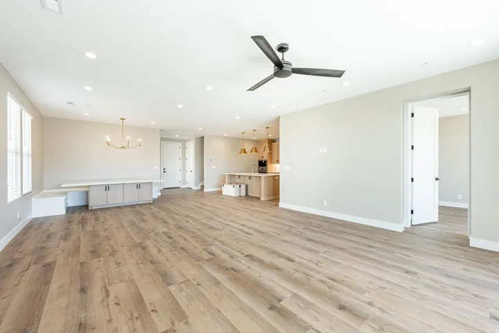 Spacious open-concept living area featuring wood-finish flooring, recessed lighting, and a contemporary ceiling fan