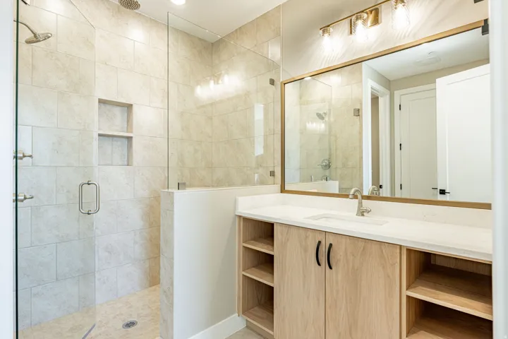 Glass-enclosed shower with tile surround and built-in shelving