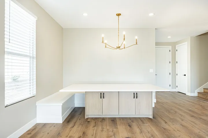 Wood-finish flooring, built-in bench seating, recessed lighting, gold-tone chandelier, and light wood-finish cabinetry with black hardware