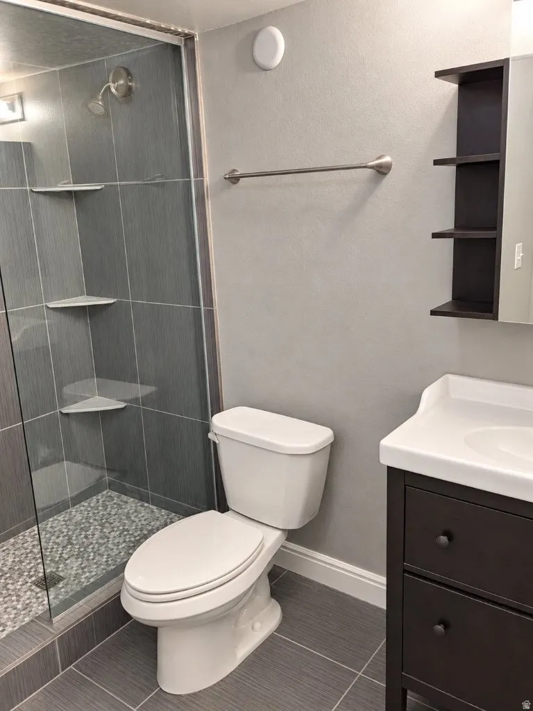 Glass-enclosed shower with a pebble floor and built-in corner shelves