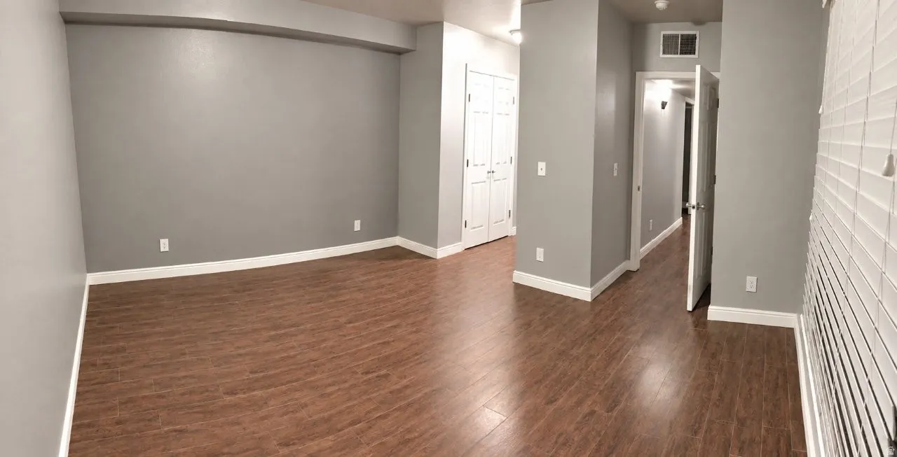 Wood-finish flooring, light grey wall paint, white trim, white window blinds, and white bi-fold closet doors