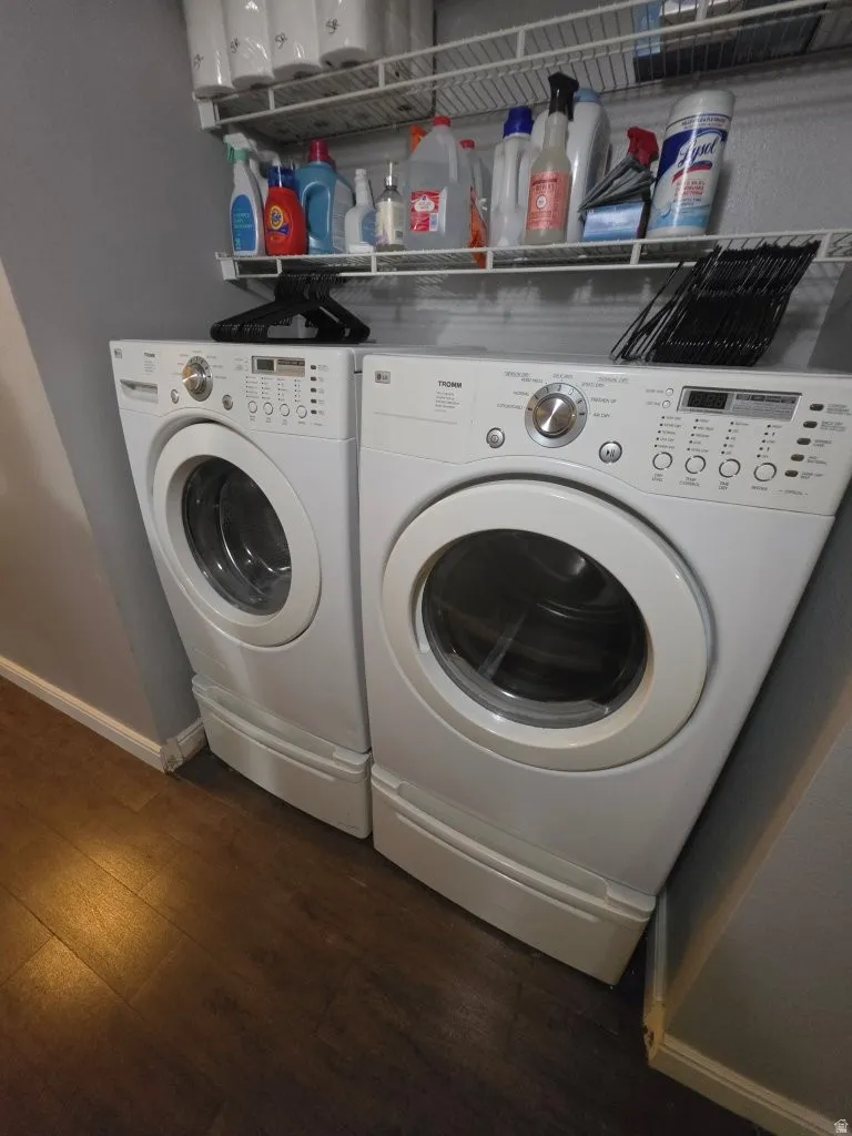 Front-loading washer and dryer on elevated pedestals, complemented by two wire shelving units, and wood-finish flooring