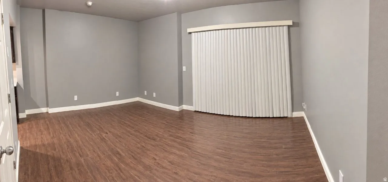 Spacious interior featuring wood-finish flooring, light gray wall paint, white trim, and vertical blinds