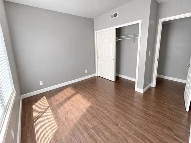 Wood-finish flooring, neutral gray wall tones, white trim, and a built-in closet with sliding doors