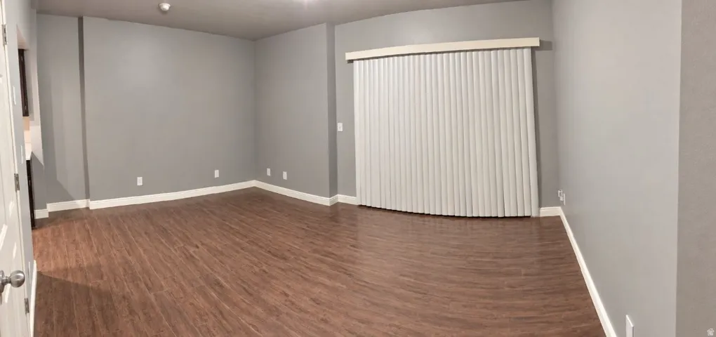 Spacious interior featuring wood-finish flooring, light gray wall paint, white trim, and vertical blinds