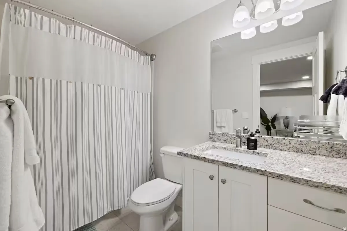 White vanity with ample cabinet storage, undermount sink, and speckled stone countertop