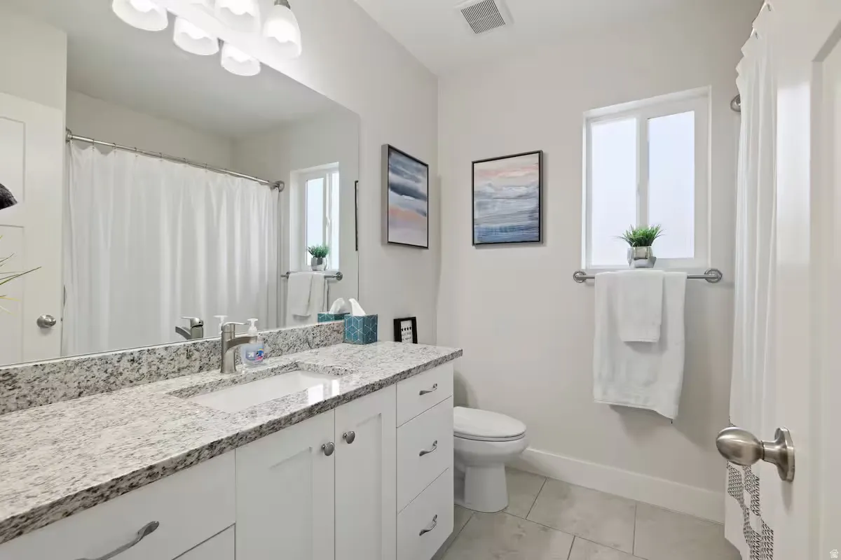 White vanity with a stone countertop, an undermount sink, and a chrome faucet