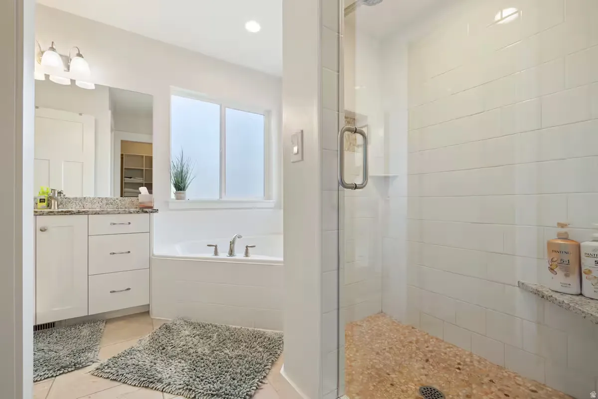 Walk-in shower with natural stone-tiled floor and glass enclosure